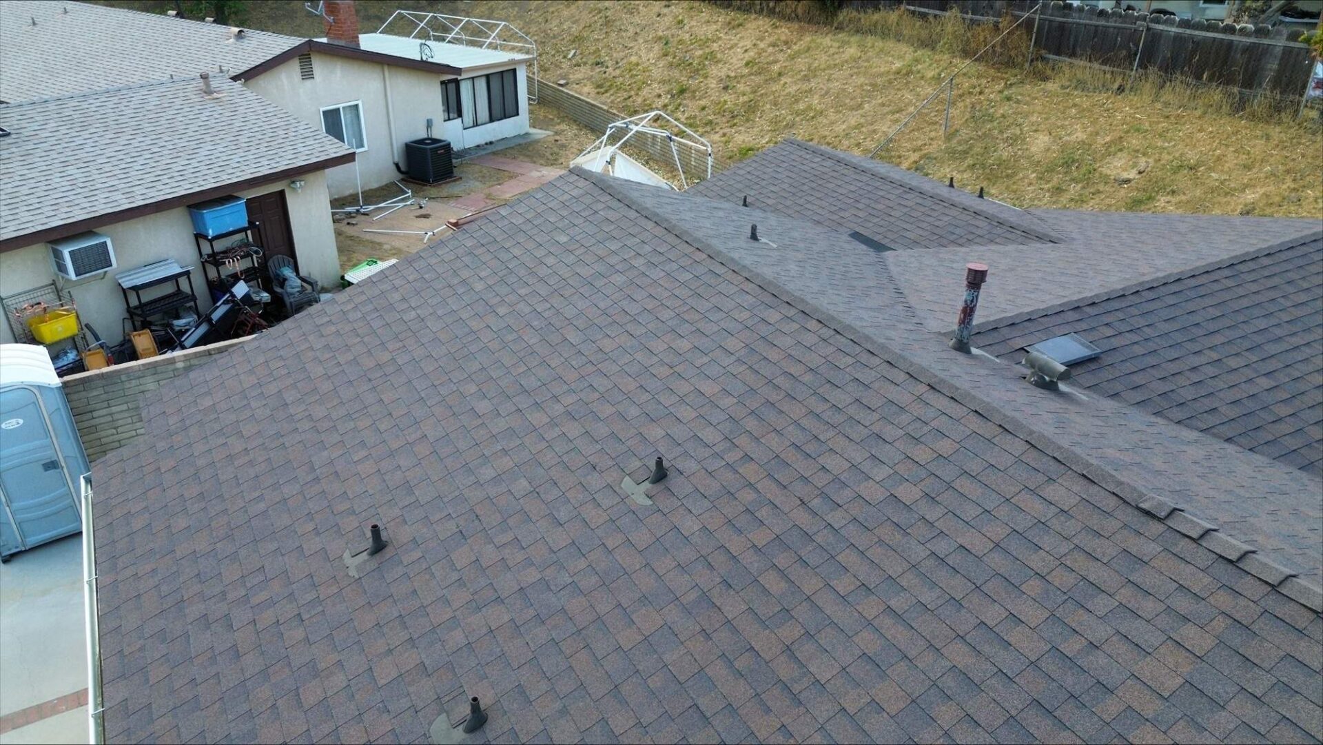 A rooftop with multiple vents and a nearby white sprinkler system.