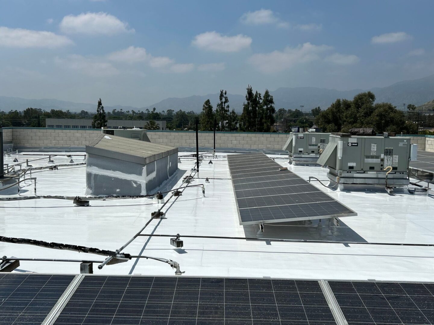 Solar panels installed on a white rooftop with a cloudy sky background.