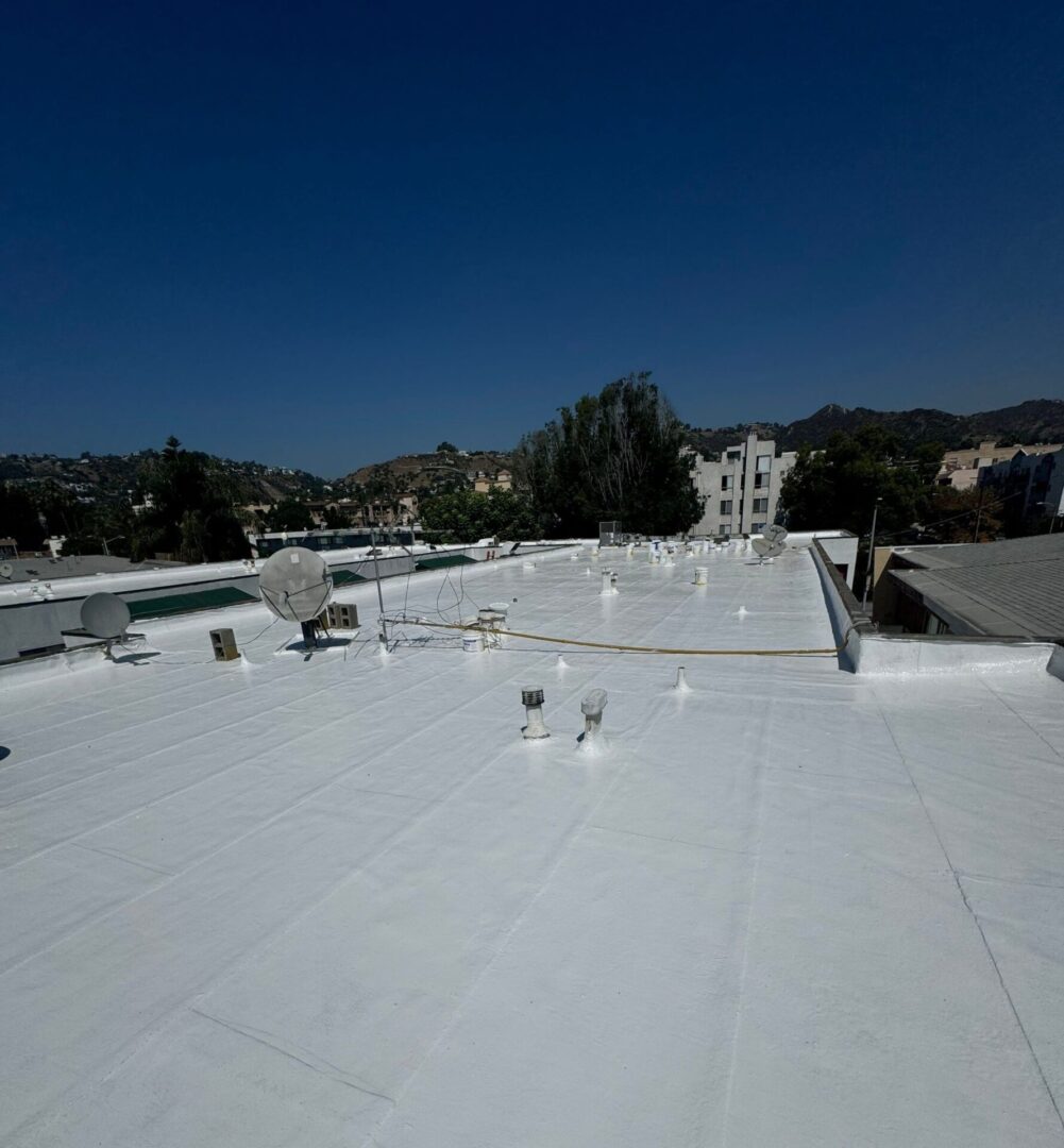Expansive white rooftop under a clear blue sky with distant hills.