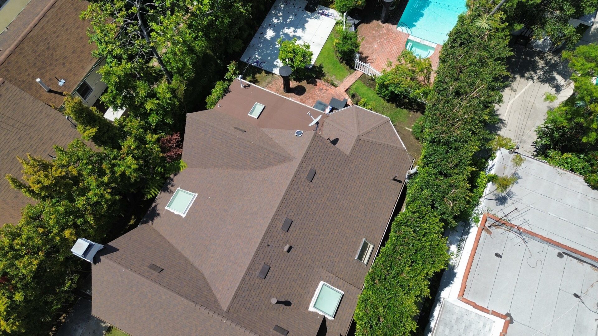 Aerial view of a house with a brown roof surrounded by trees.