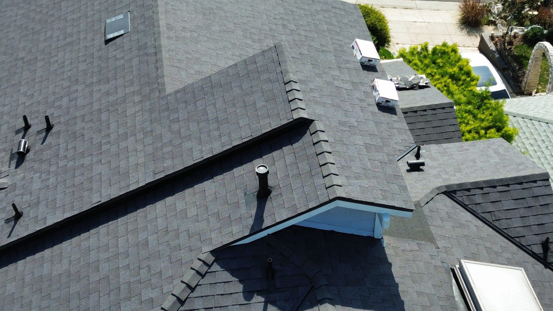 Aerial view of a house roof with dark shingles and vents.