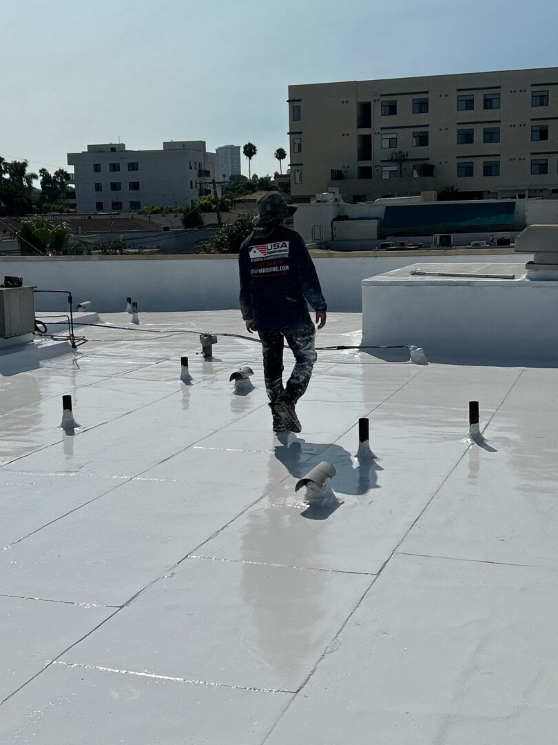 Person walking on a white rooftop with ventilation pipes.