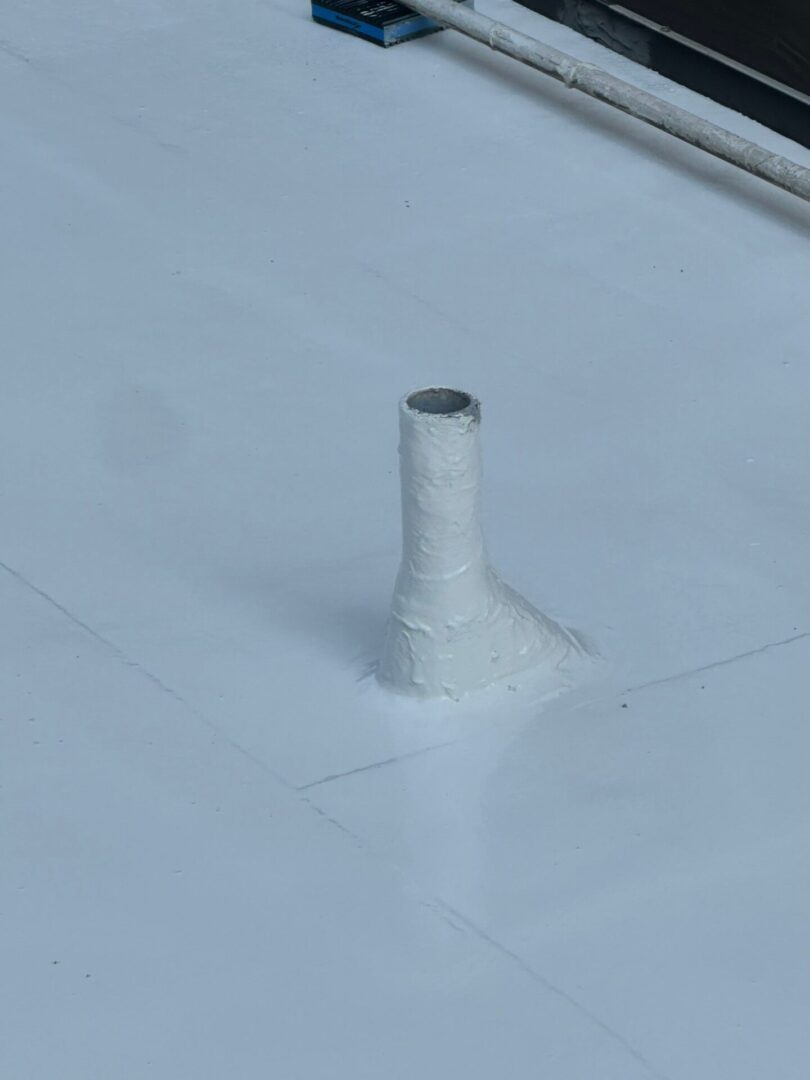 White vent pipe protruding from a flat white roof.