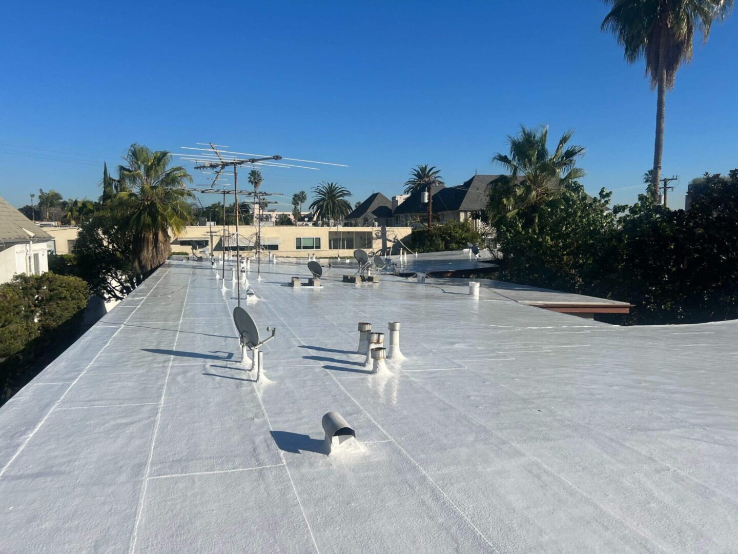 Newly coated white flat roof with clear blue sky.