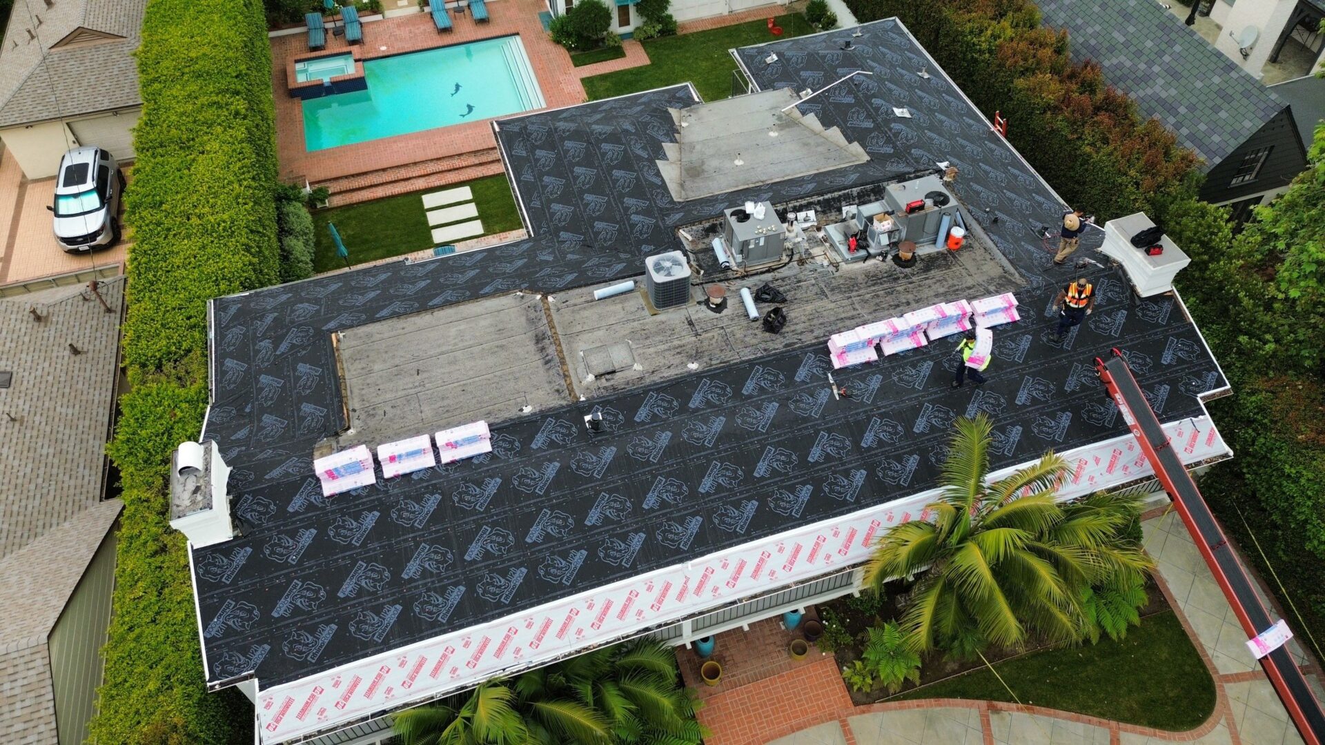 A rooftop with solar panels and air conditioning units beside a swimming pool.