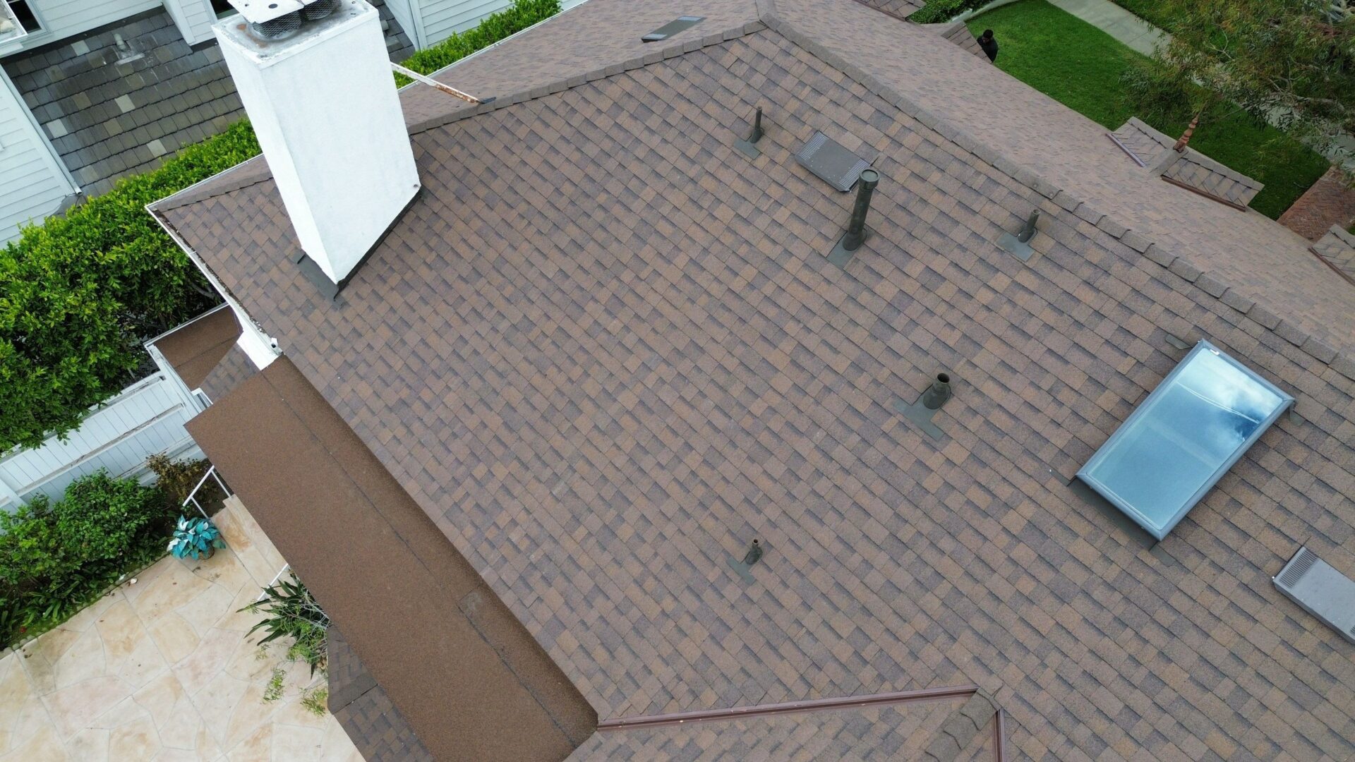 A rooftop with brown shingles and several vents.