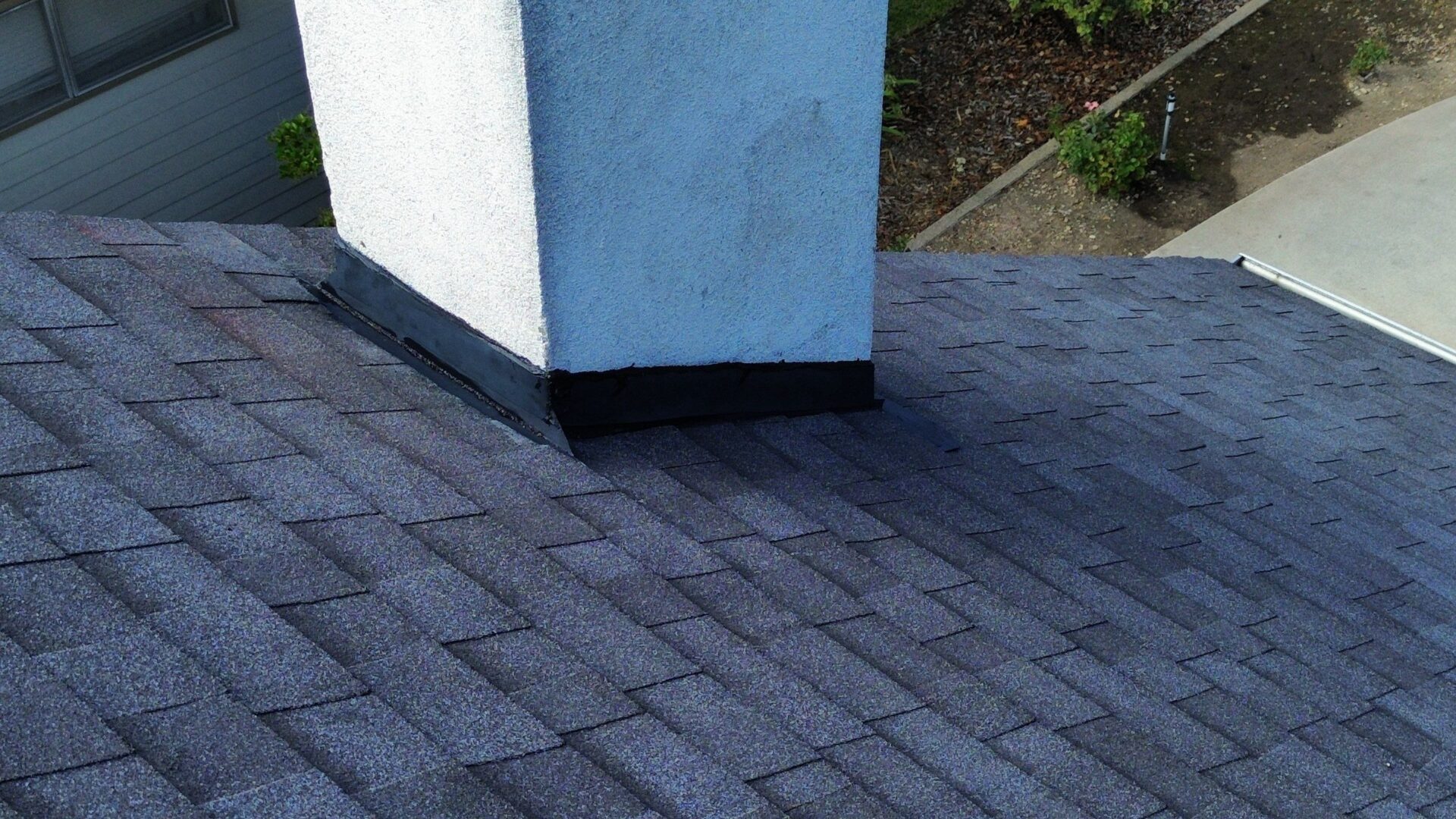 Newly laid gray brick pavement around a white building corner.