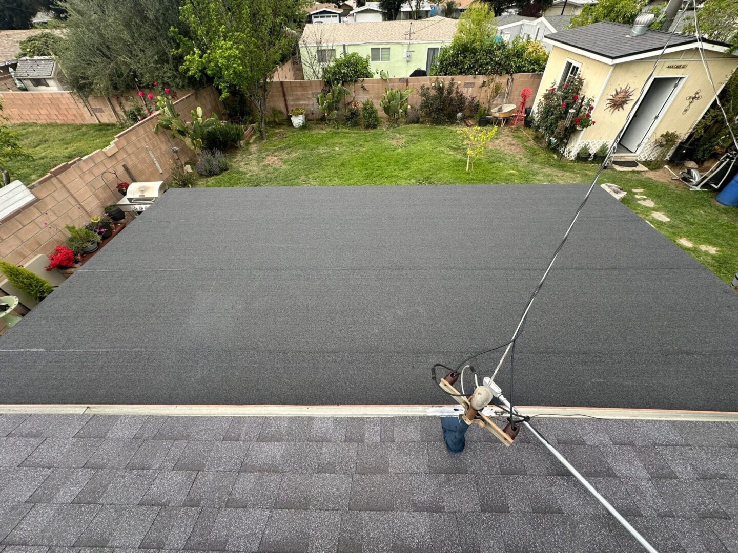 A rooftop being covered with black roofing material.