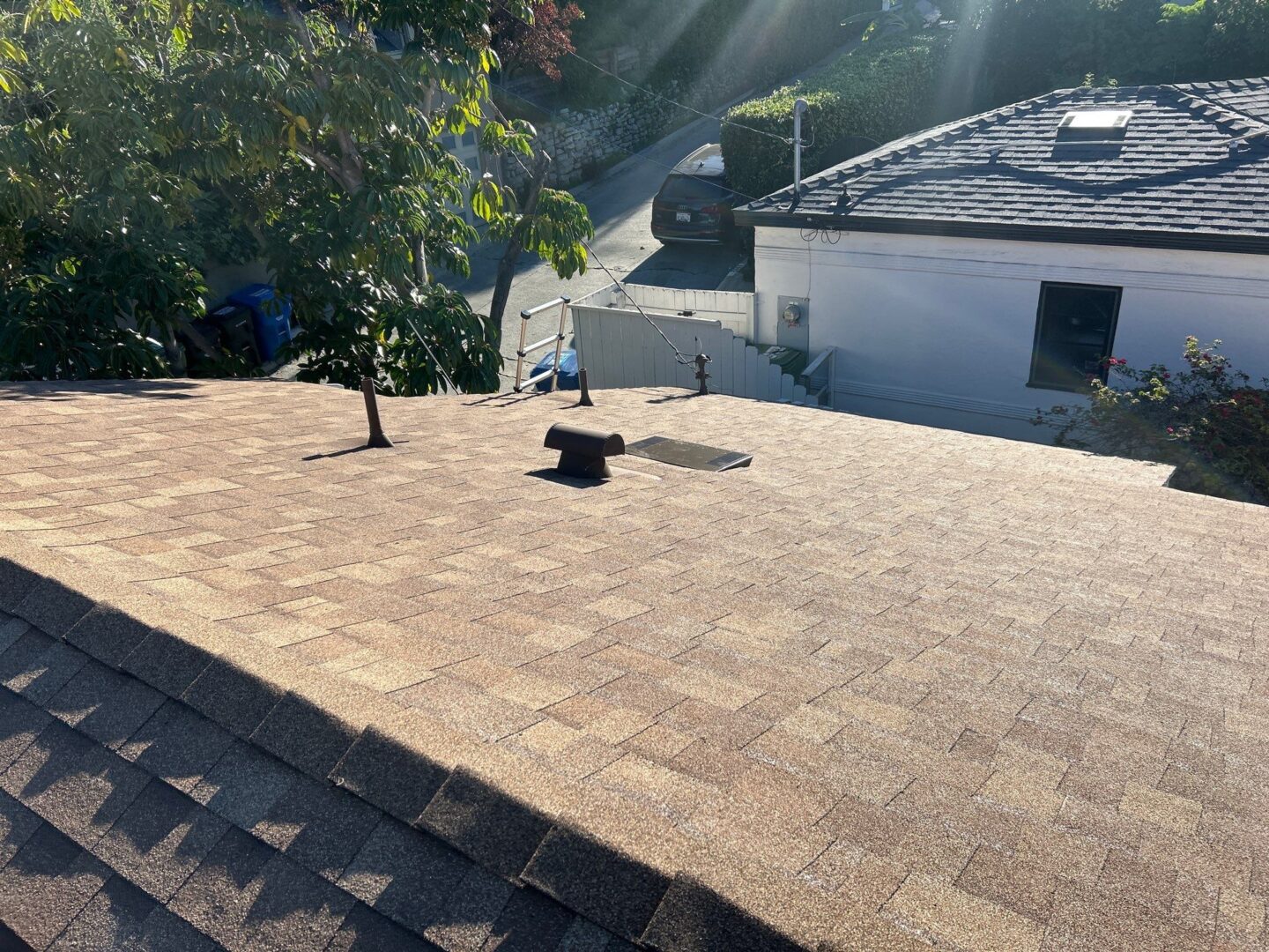 A rooftop with new shingles under bright sunlight.