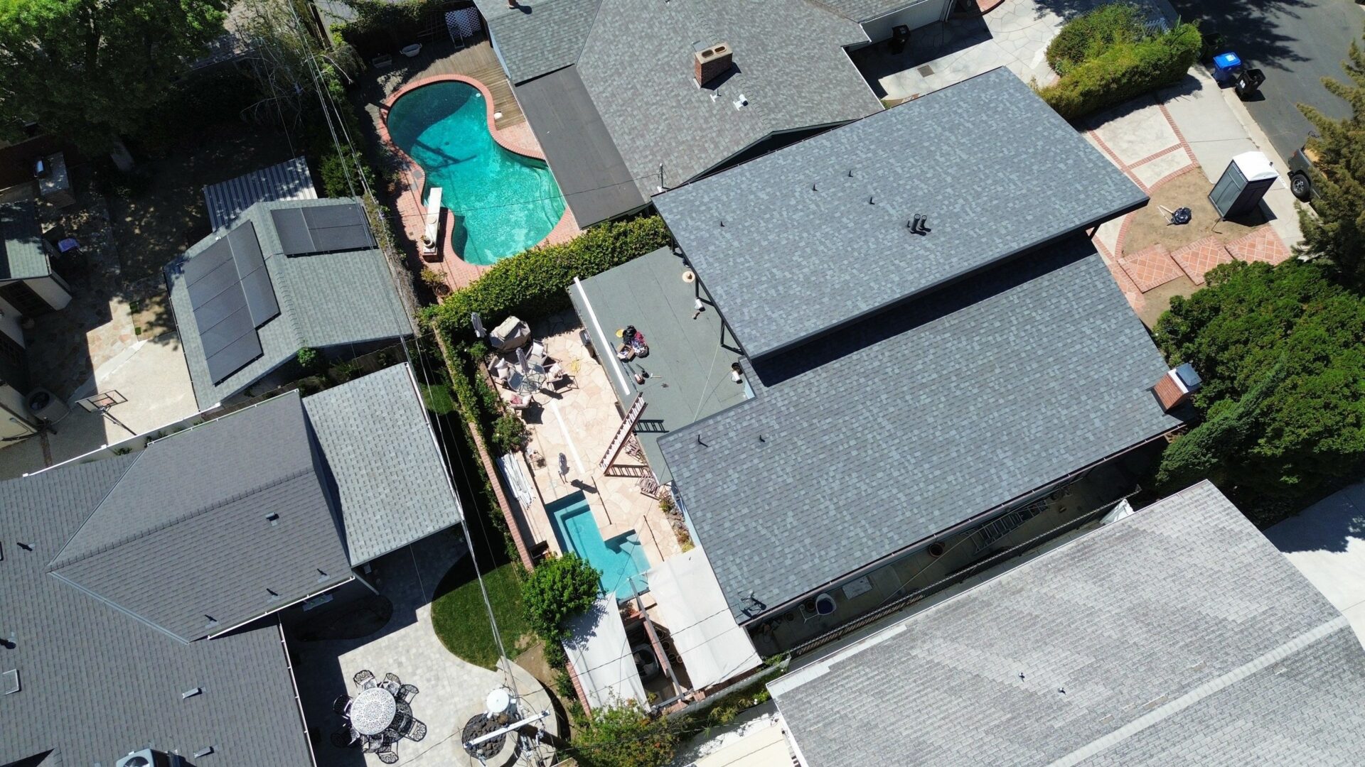 Aerial view of houses with swimming pools and outdoor seating areas.