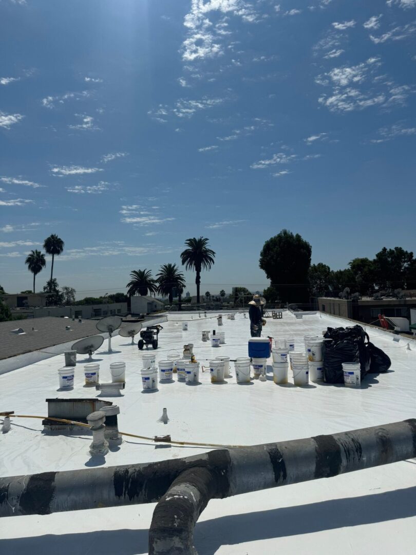 Rooftop view with air conditioning units under a clear sky and palm trees.