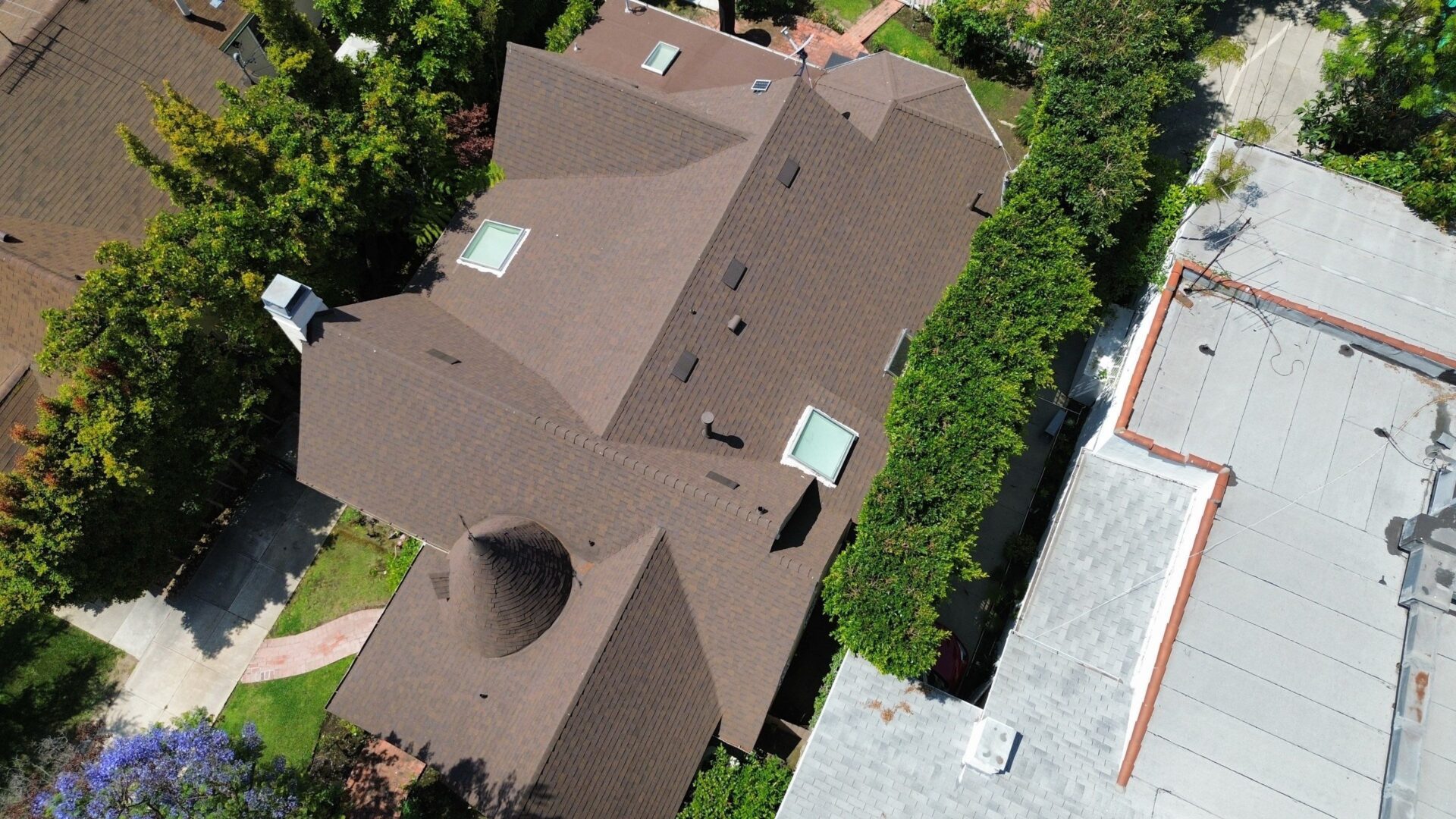 Aerial view of a large brown-roofed residential house surrounded by greenery.