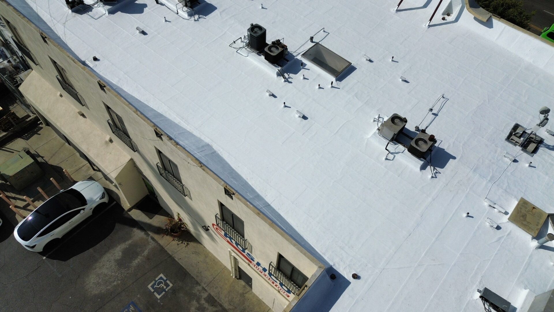 White flat roof with HVAC units and vents on a commercial building.