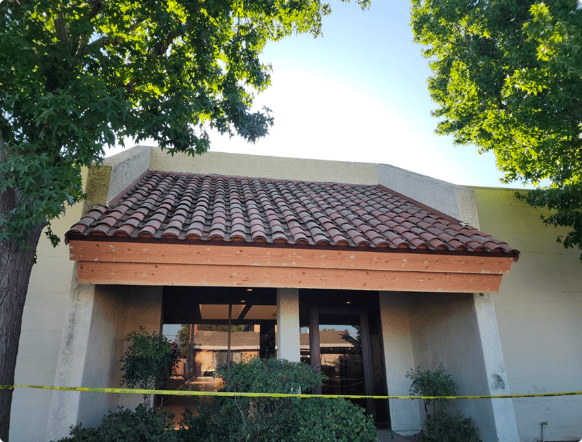 Cozy building with a tiled roof framed by green trees.