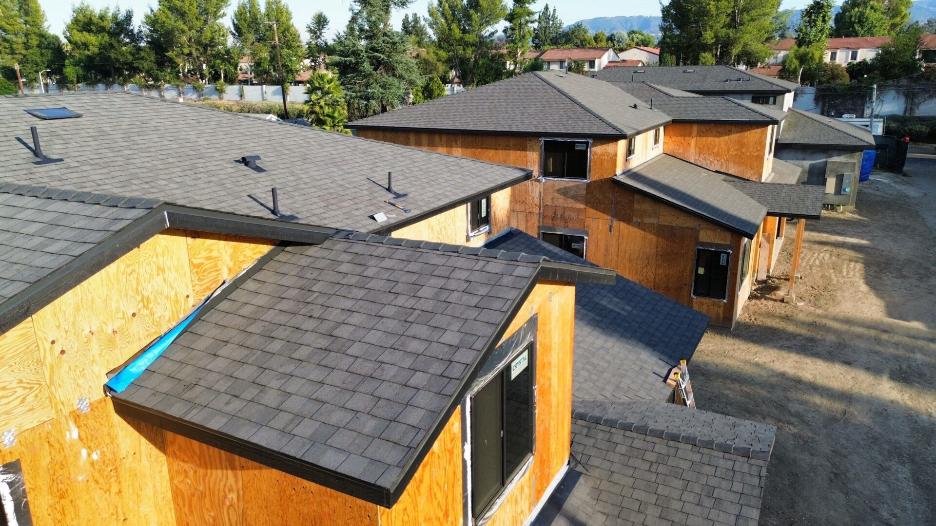Modern houses with dark shingled roofs and wooden siding under clear skies.