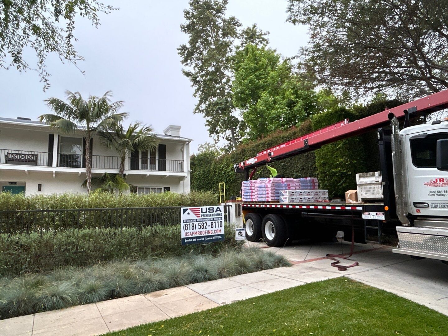 Truck loaded with boxes parked beside a modern house in a green neighborhood.
