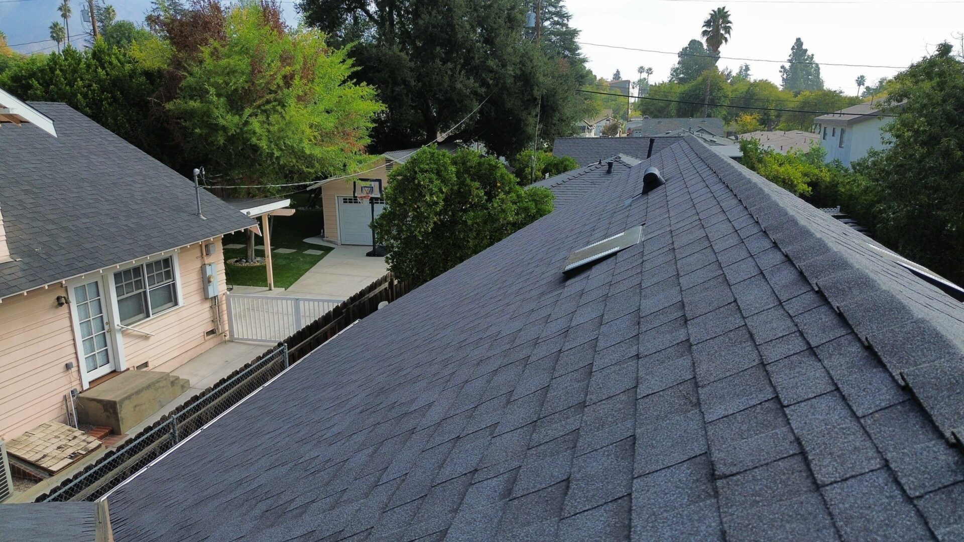 A rooftop with solar panels and a suburban neighborhood in the background.