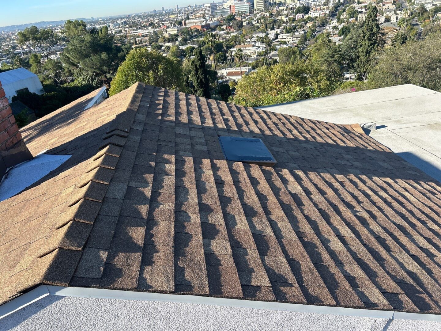 A rooftop with new asphalt shingles under bright daylight.