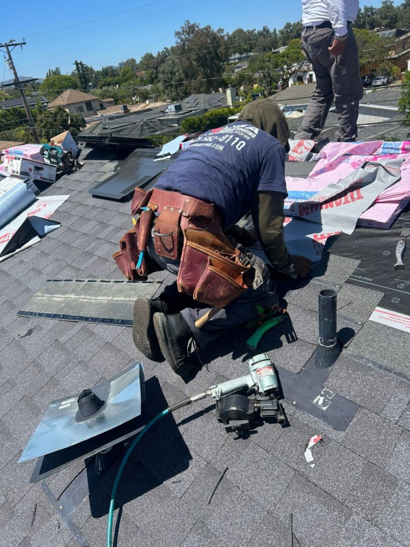 Roofer installs solar mounting equipment on a shingled roof under clear skies.