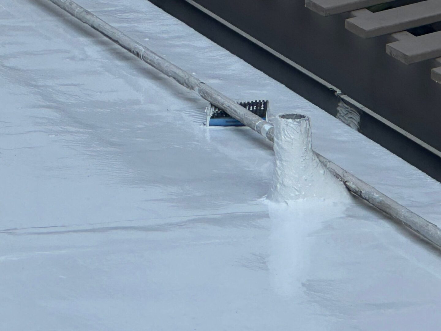 Close-up of a white pipe on a waterproofed roof.