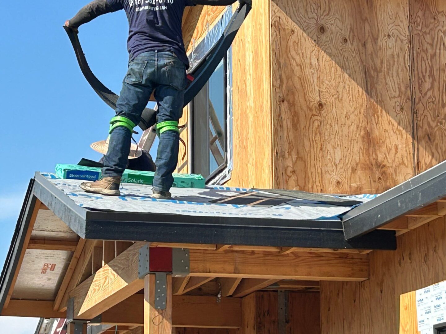 Worker installing insulation panels on a house under construction.