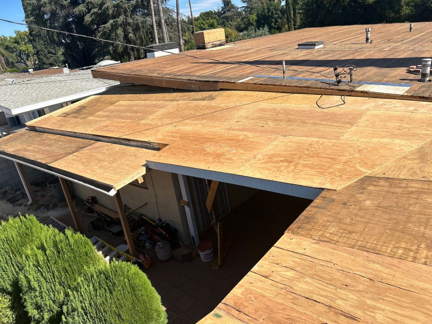 Roof undergoing renovation with plywood sheets being installed.