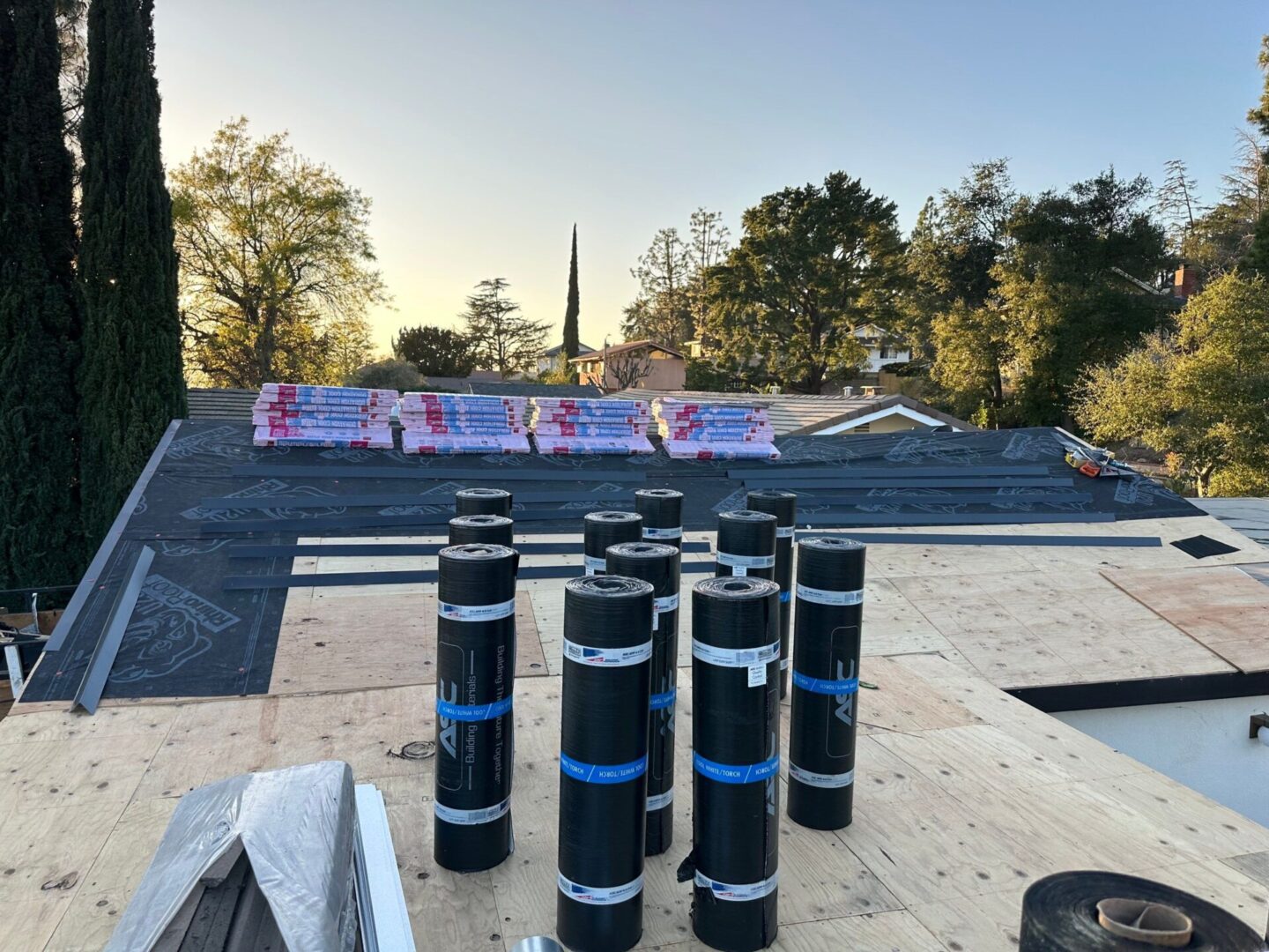 Roofing project underway with insulation rolls and a church steeple in the background.