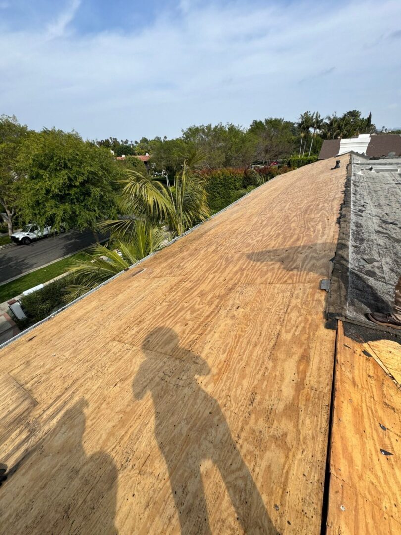 A newly stripped roof with a shadow of a person taking the photo.