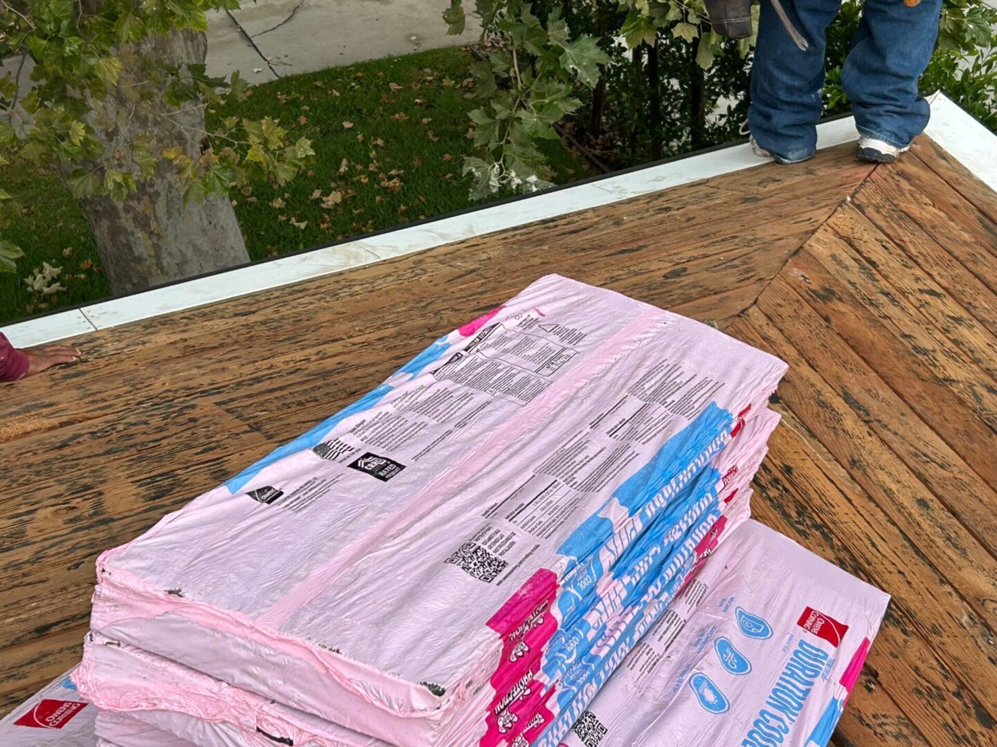 Stack of pink insulation panels on a wooden surface outdoors.