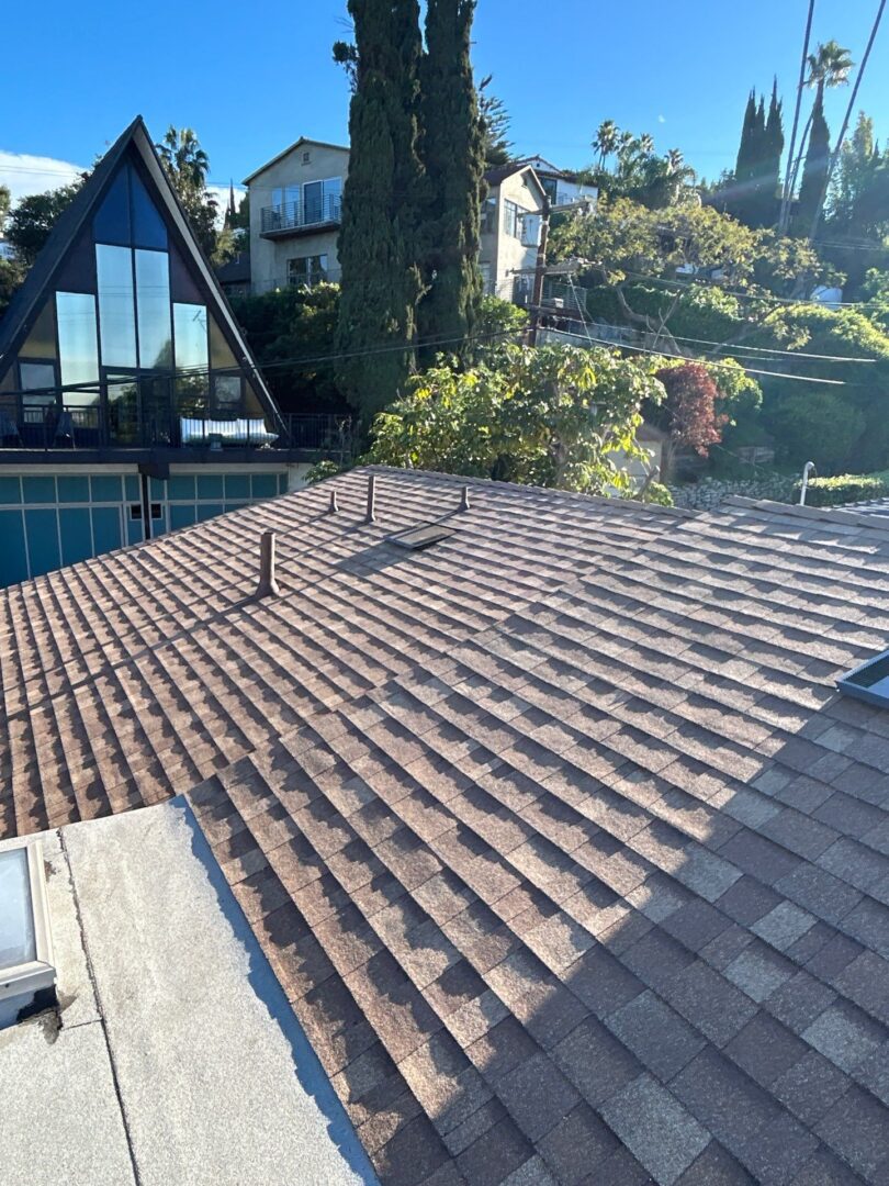 Newly installed brown roof tiles on a sloped roof under clear skies.