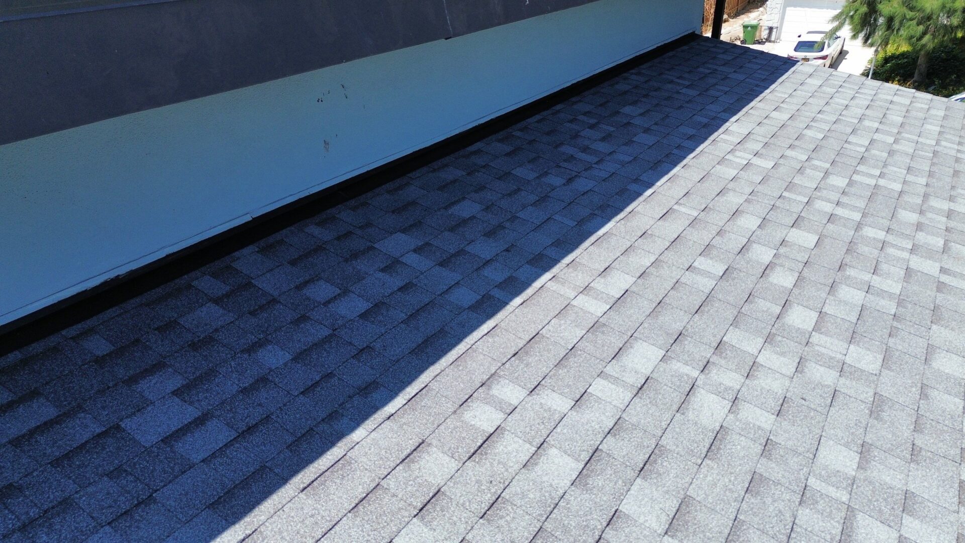A rooftop with gray shingles casting shadows.