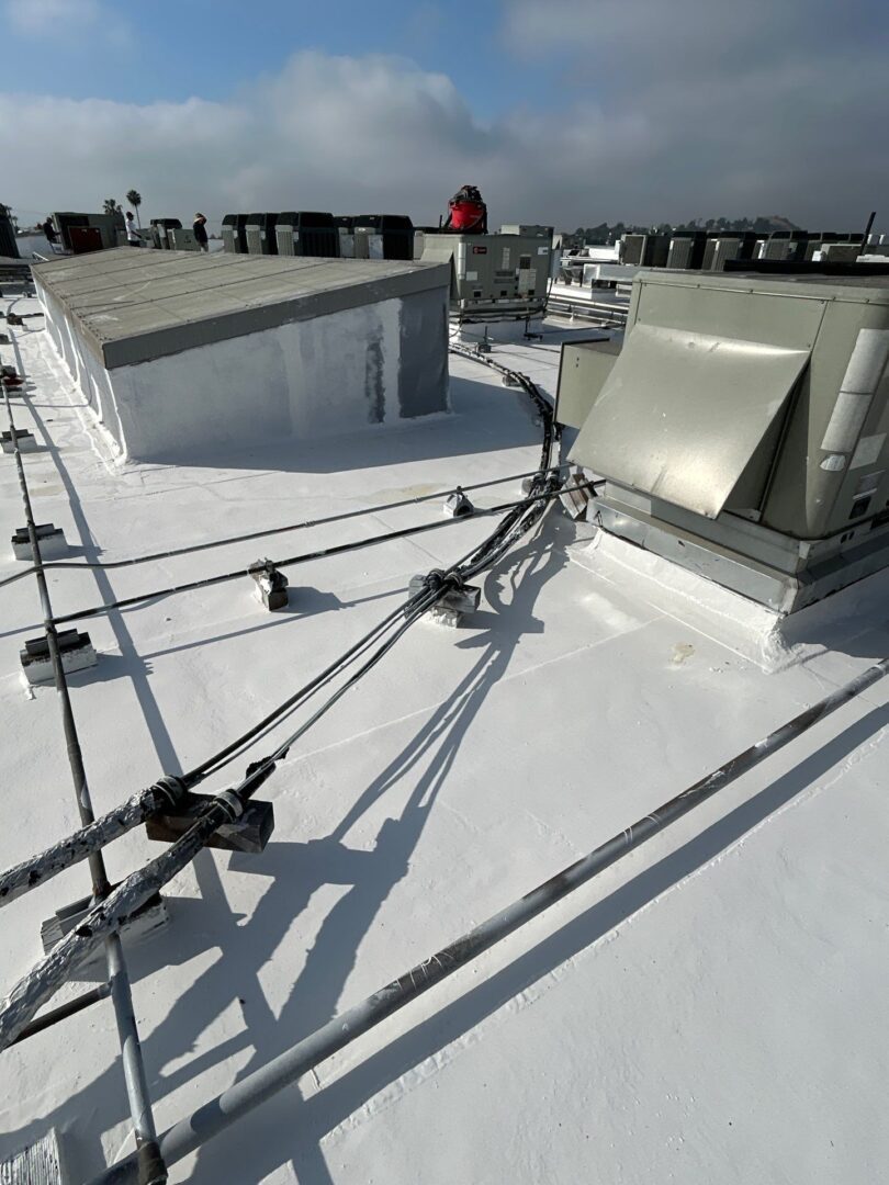 Rooftop with white coating and metal structures under a clear sky.