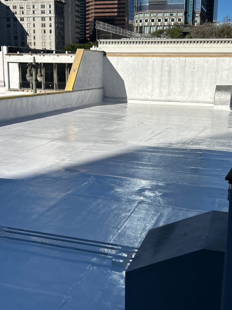 A rooftop covered with a smooth, reflective silver waterproof membrane.
