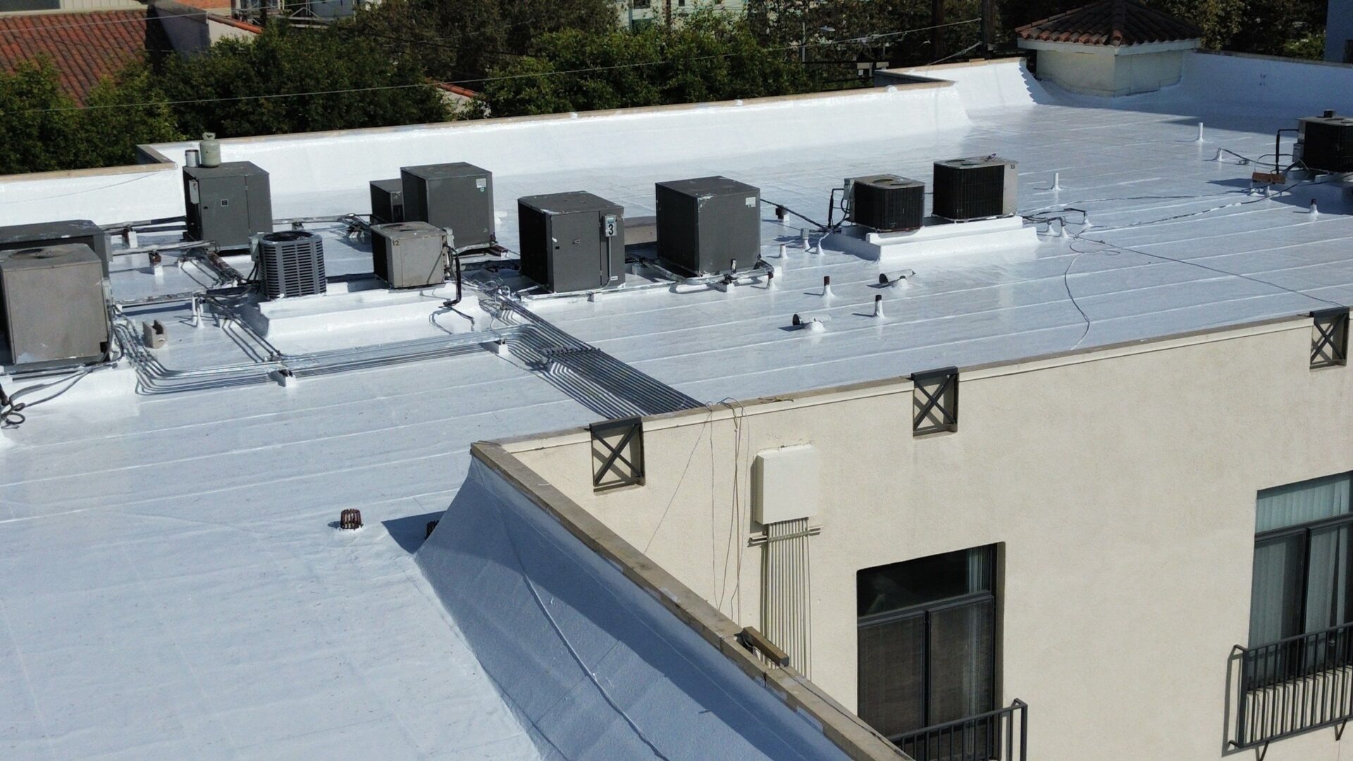 Rooftop with multiple HVAC units and vents on a flat surface.