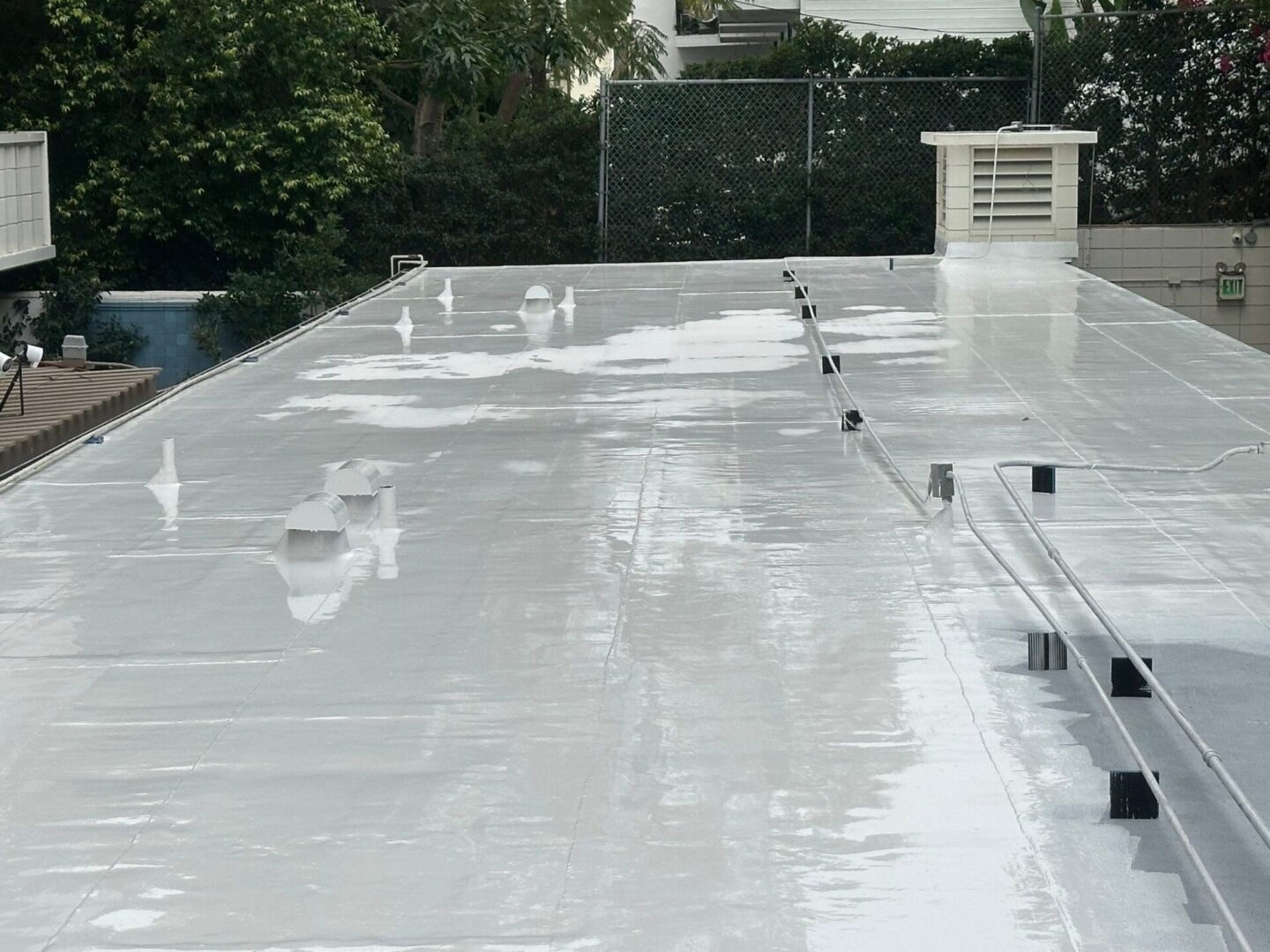 A reflective, wet rooftop with water puddles and ventilation units.