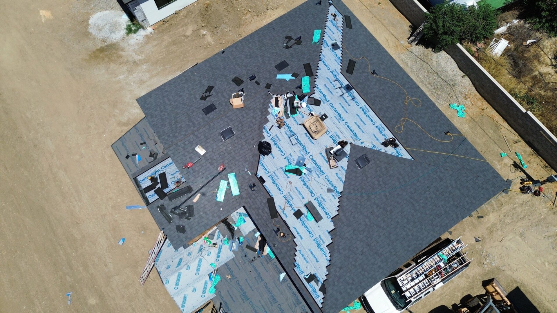 Aerial view of roofers installing shingles on a residential house.