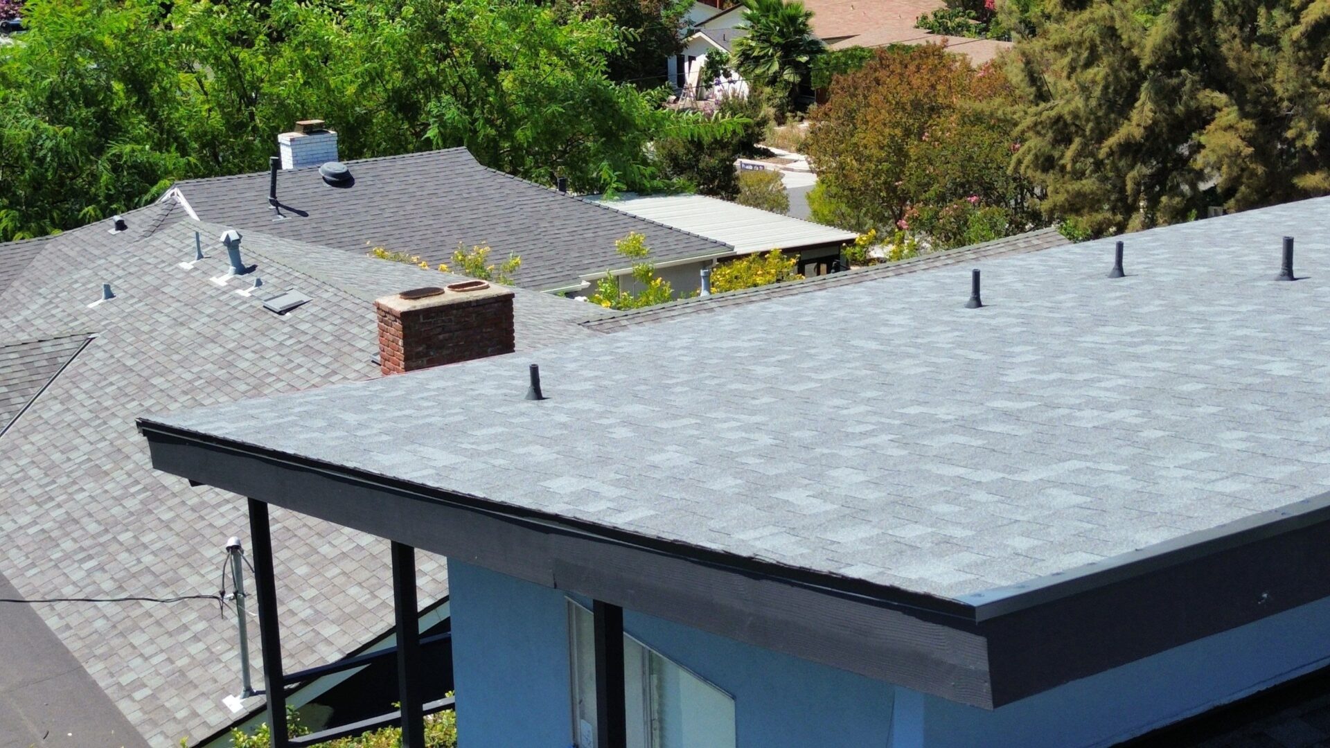 Flat roof with multiple vents and a chimney on a residential building.