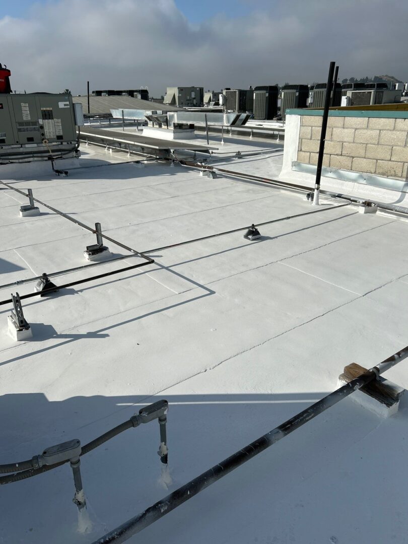 Flat white rooftop with ventilation pipes and equipment.