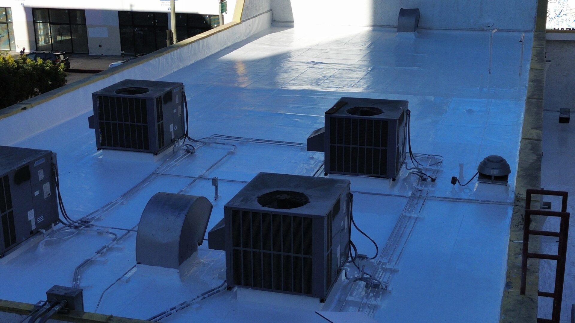 Air conditioning units installed on a flat rooftop with ductwork.