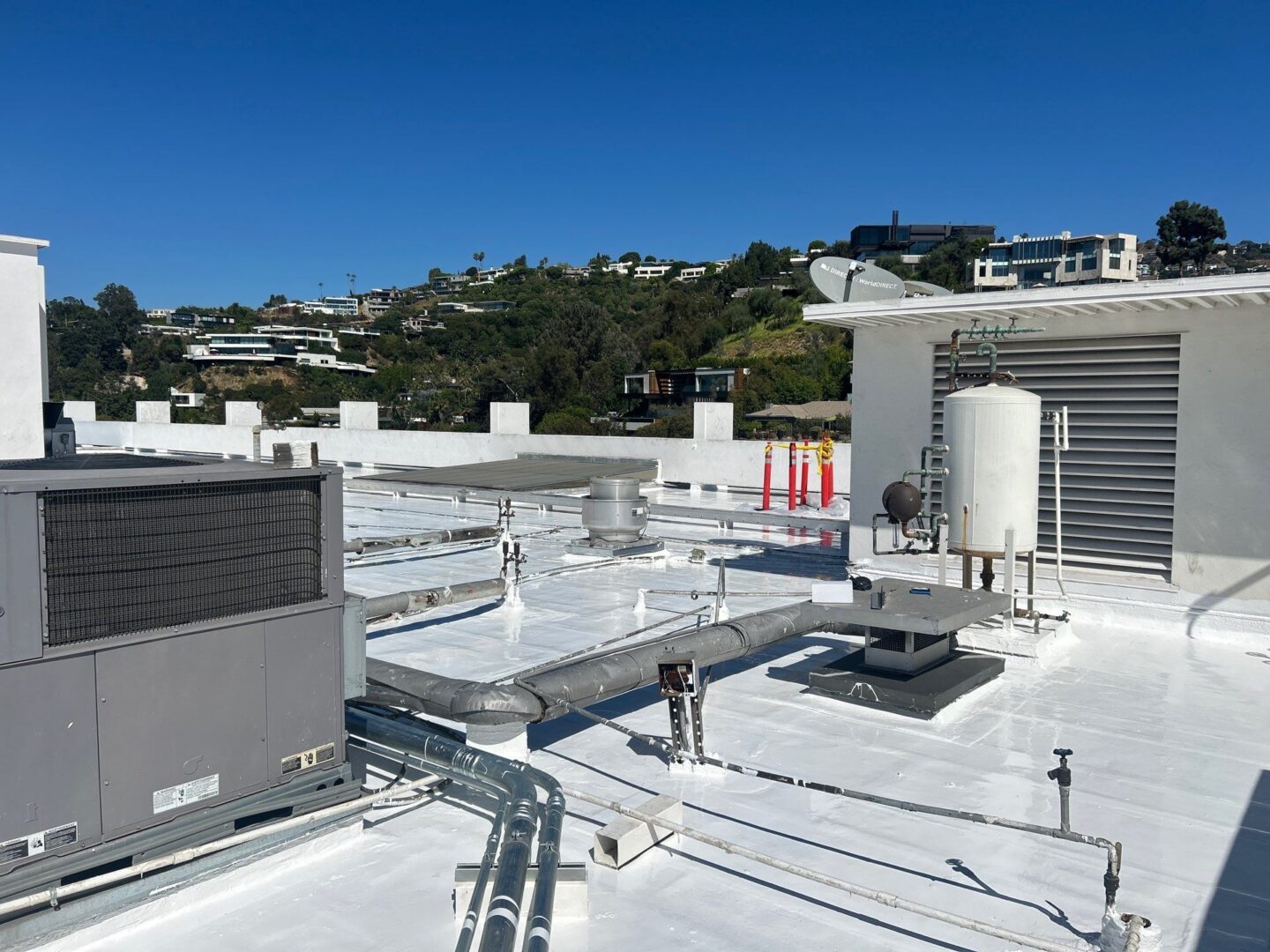 Rooftop with HVAC units and a white surface under clear sky.