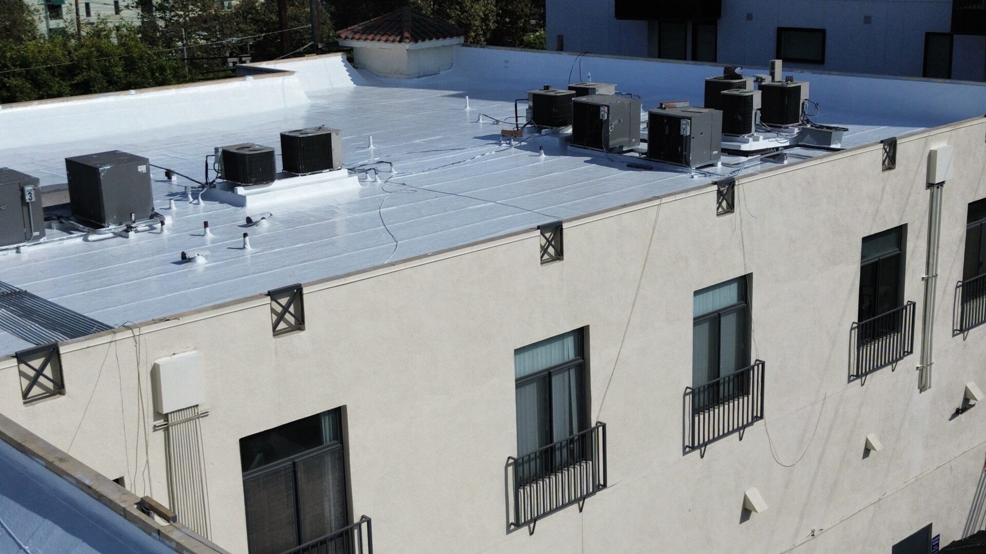 Air conditioning units installed on a white building's rooftop.