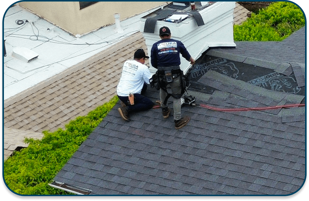 Two workers inspecting a rooftop with tools and safety gear.