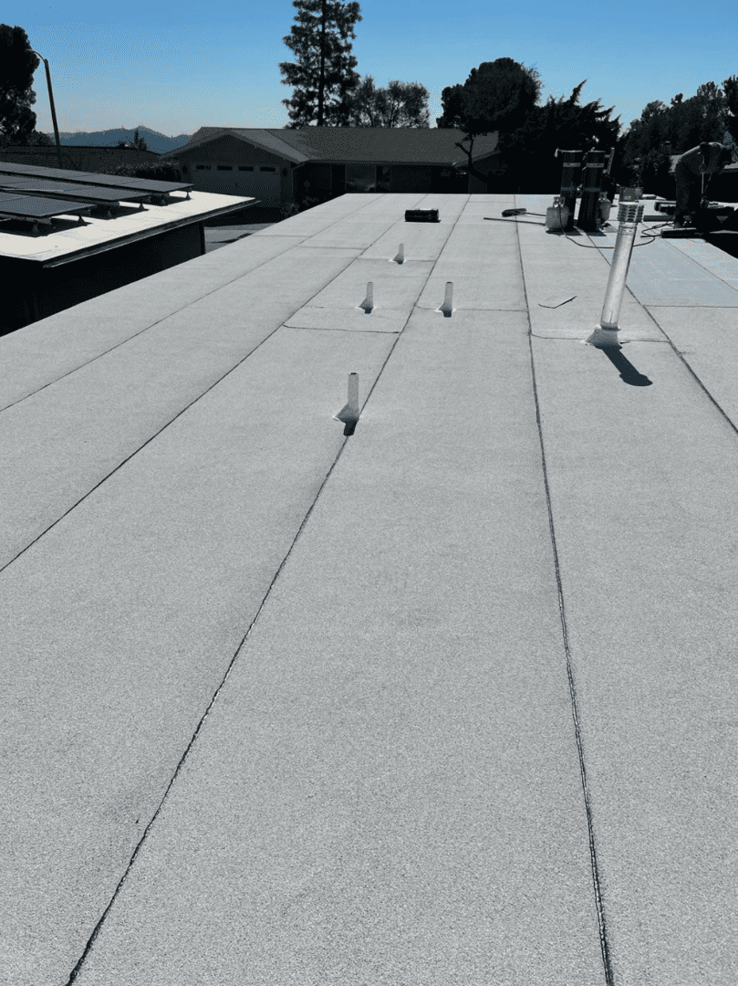 Rooftop with ventilation pipes casting shadows under sunlight.
