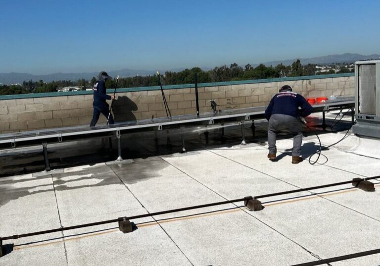 Crew pressure-washing a flat commercial roof