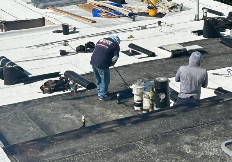 Roofers installing black membrane and materials